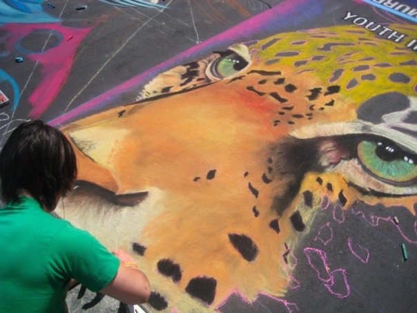 Artist in process of creating a street painting